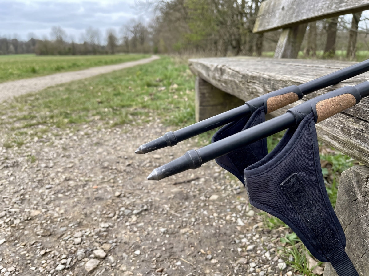 Zwei moderne Nordic-Blading-Stöcke mit Hartmetallspitzen an eine Holzbank am Feldweg gelehnt